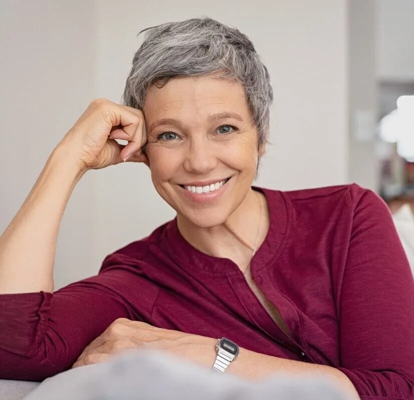 Mature woman smiling and sitting on a couch - Dentaluxe