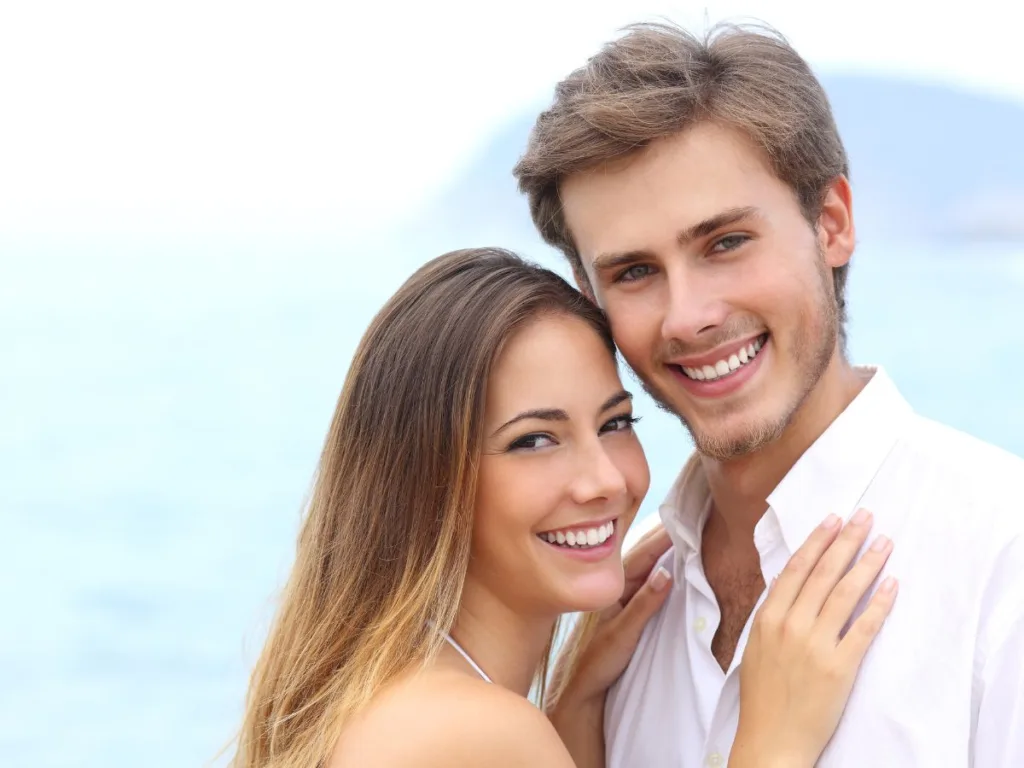 adults embrace on the beach and wonder how dental implant broke