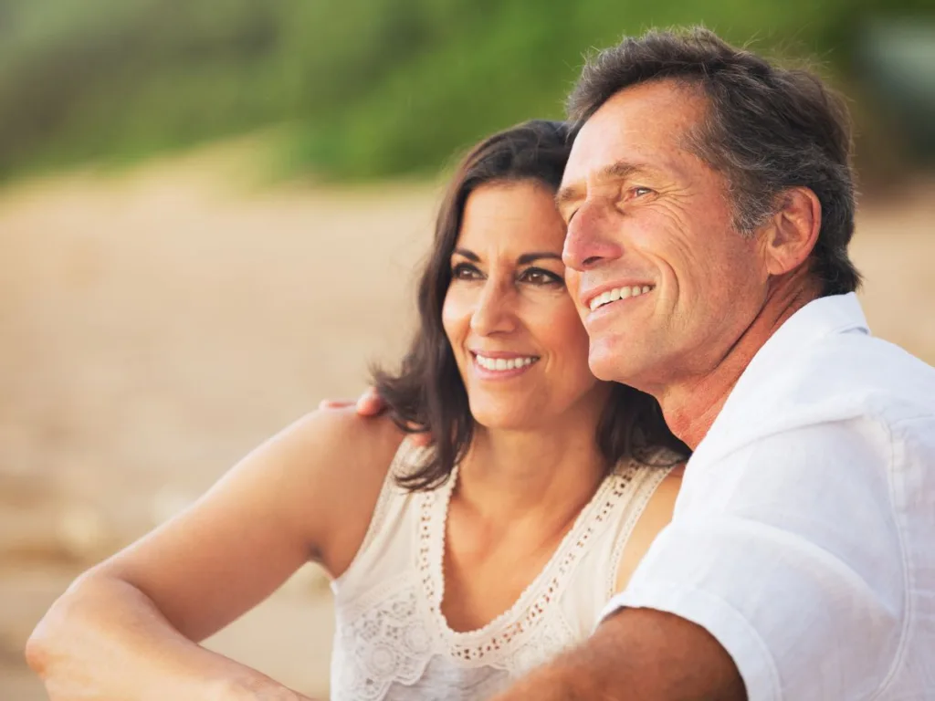 couple watches sunset on the beach while talking tooth replacement